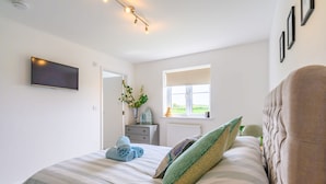 Une chambre à coucher avec un lit, une télévision, une fenêtre donnant sur un beau paysage et une commode.