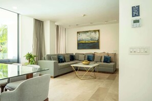 Uma sala de estar moderna com uma mesa de jantar de vidro, um sofá seccional e um quadro na parede.