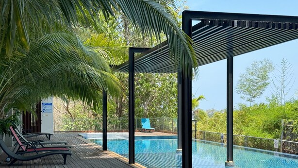 A wooden deck with a pool, lounge chairs, and a safety sign.