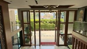 A hotel lobby with a glass door leading to a courtyard, a chandelier, and a painting on the wall.