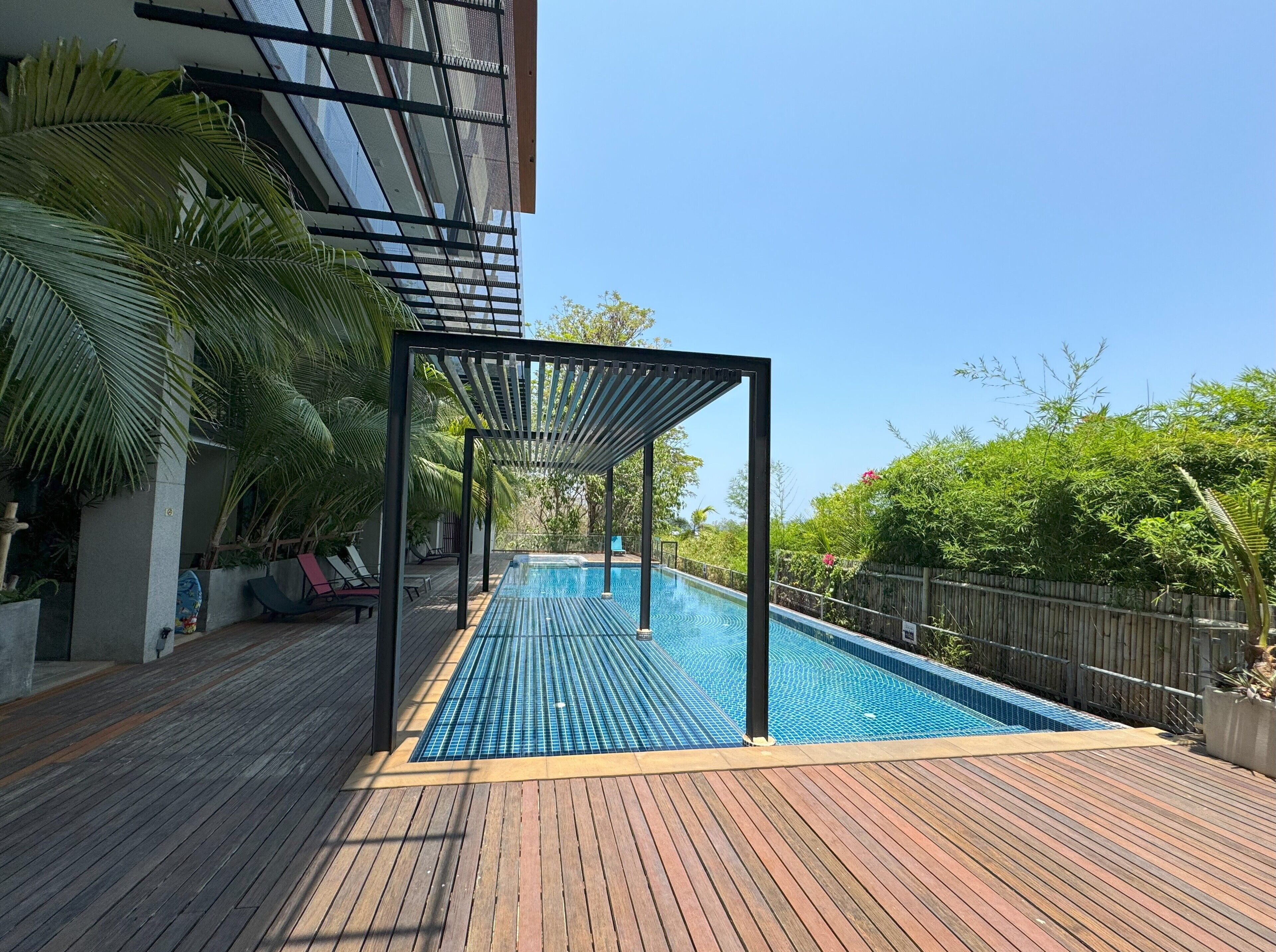 A swimming pool with a wooden deck and a pergola structure.