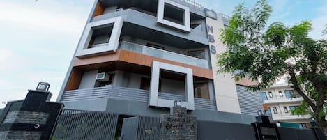 A modern multi-story building with balconies and a gated entrance.