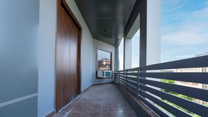 A corridor with a wooden door, a view of buildings, and a balcony with a railing. - Letstay Business Suite (Noida)