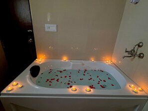A bathtub with rose petals and candles. - Letstay Business Suite (Noida)