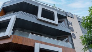 A modern building with a sign reading "NBS" and a logo above it. - Letstay Business Suite (Noida)