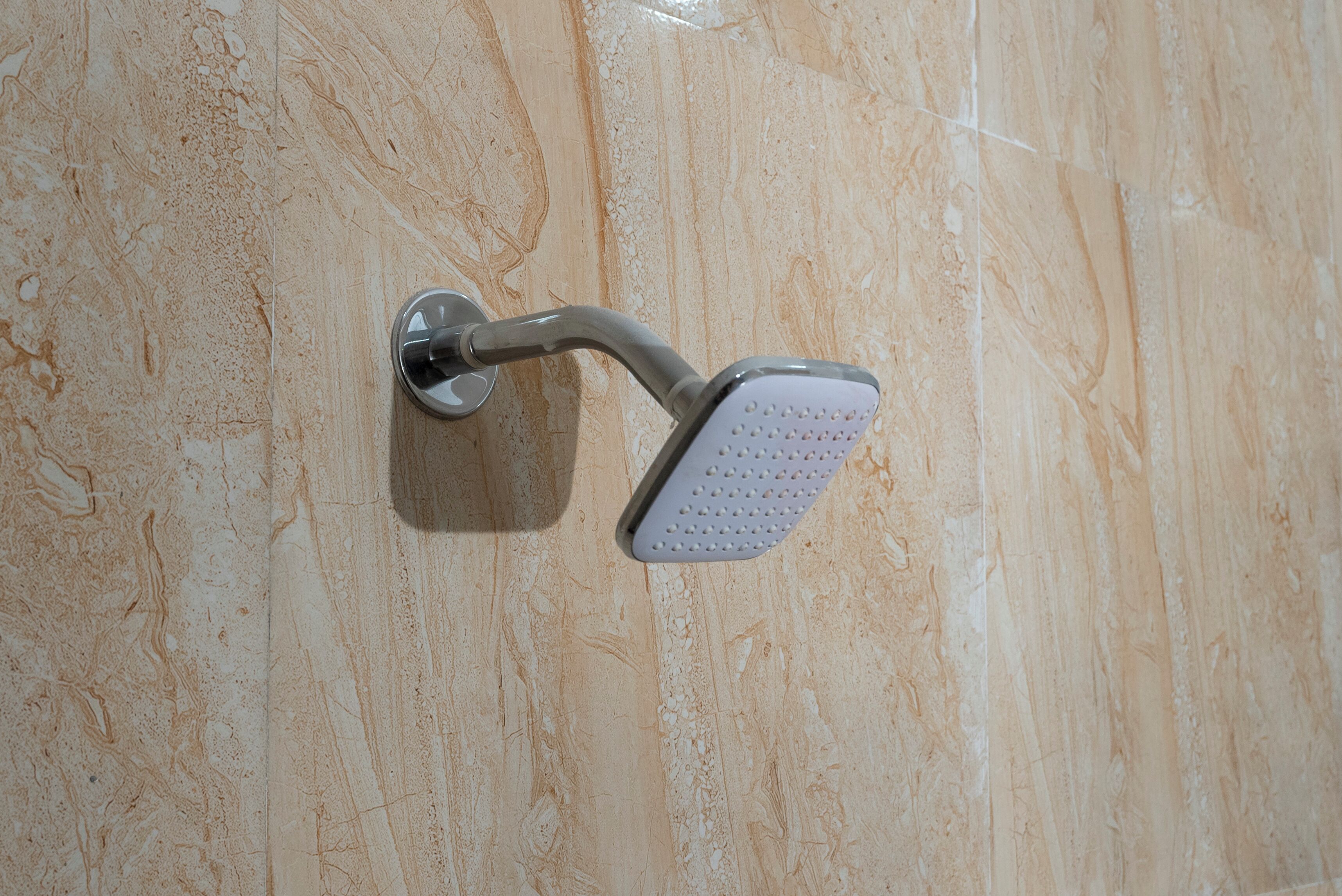 A showerhead mounted on a marble wall.