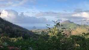 A mountainous landscape with lush greenery and a view of the sea.