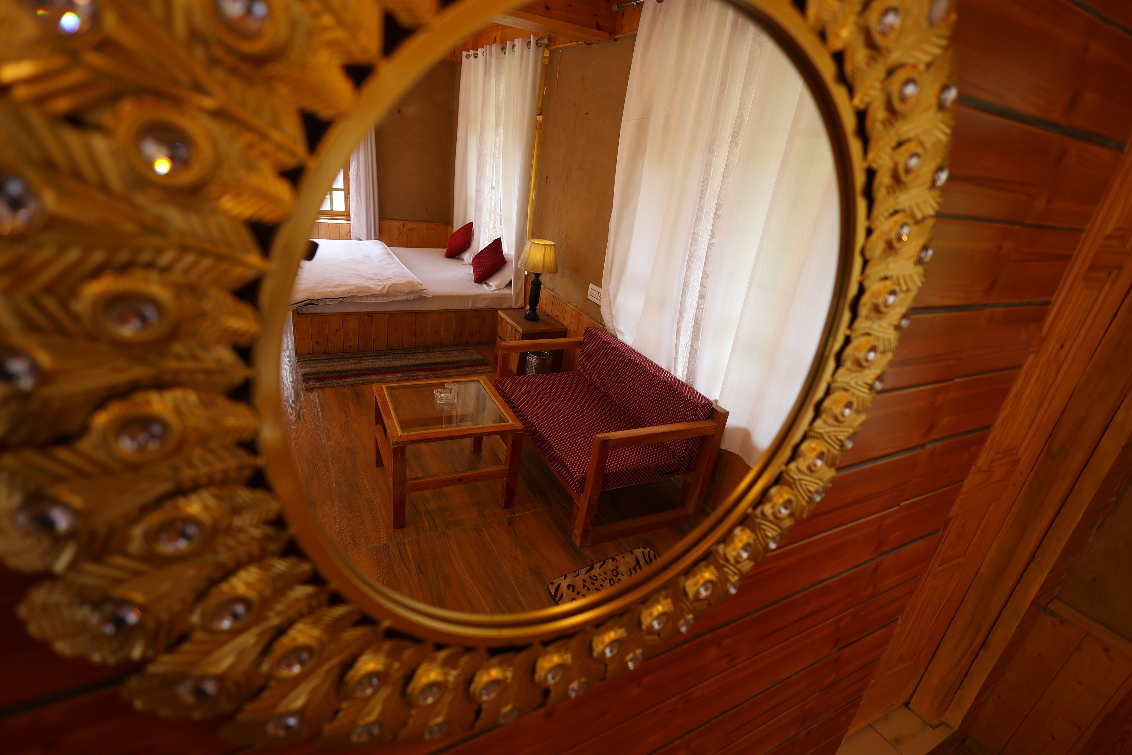 A room with a bed, a small table, and a mirror with an ornate frame.