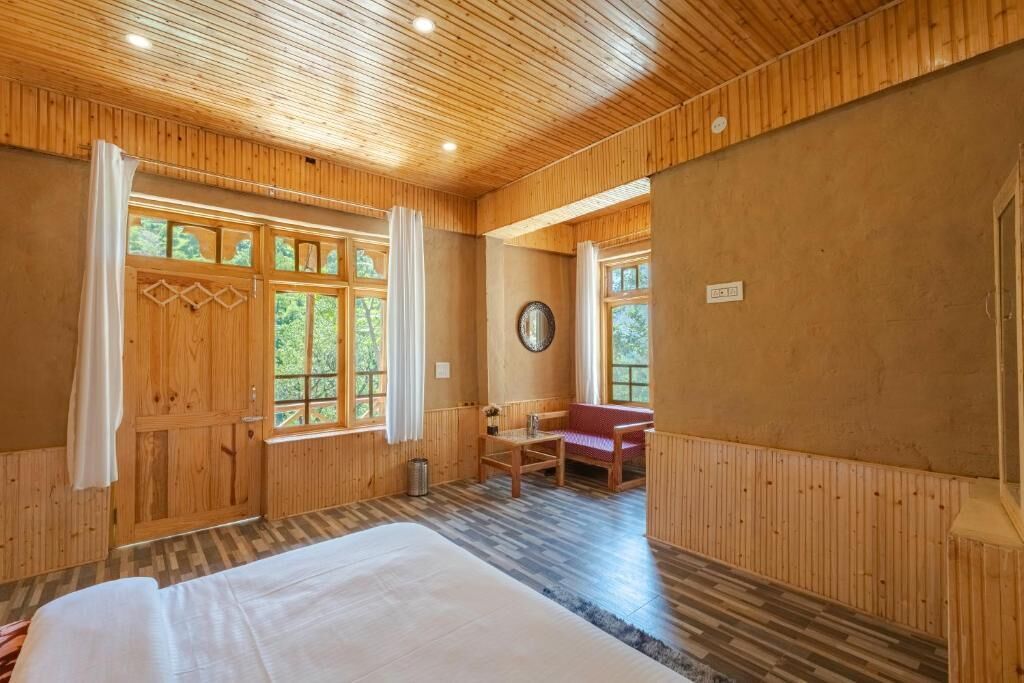 Ein Zimmer in einer Holzhütte mit einem Bett, einem Tisch und einer Bank.