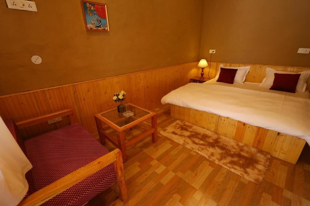 A small, cozy room with a wooden bed, a small table, and a chair.