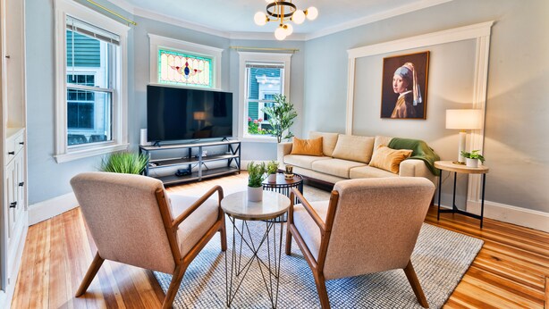 A living room with a television, sofa, two armchairs, a coffee table, and a chandelier. - Renovated Retreat /Near JFK station (Boston)