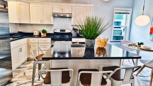 A modern kitchen with white cabinets, a central island, and pendant lighting. - Renovated Retreat /Near JFK station (Boston)