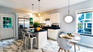 A modern kitchen with white cabinets, a marble floor, and pendant lighting. - Renovated Retreat /Near JFK station (Boston)
