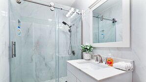A modern bathroom with a glass-enclosed shower, a white sink, and a large mirror. - Renovated Retreat /Near JFK station (Boston)