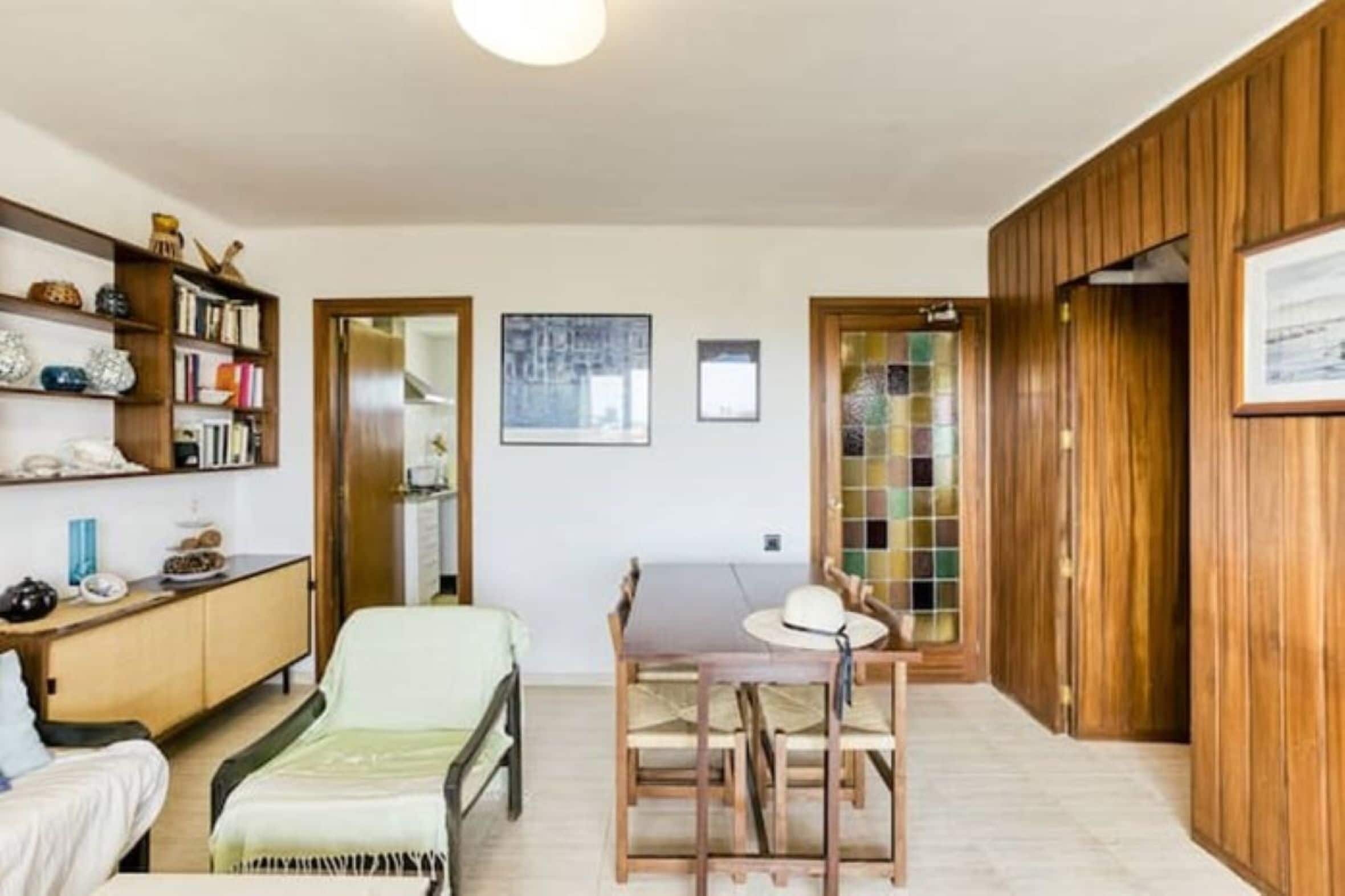 A compact living space with a dining area, a bookshelf, and a view through a door.