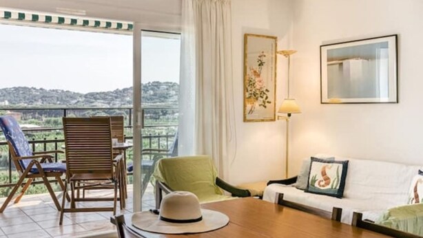 A room with a balcony, a sofa, a dining table, and a chair. - Beautiful apartment with pool and view (Sant Antoni de Calonge)