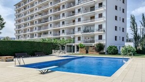 A multi-story residential building with a swimming pool in the foreground. - Beautiful apartment with pool and view (Sant Antoni de Calonge)