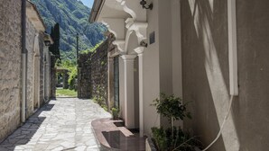 A narrow stone pathway leading to a building with a mountain backdrop. - Zukic Apartments RIsan  (Risan)