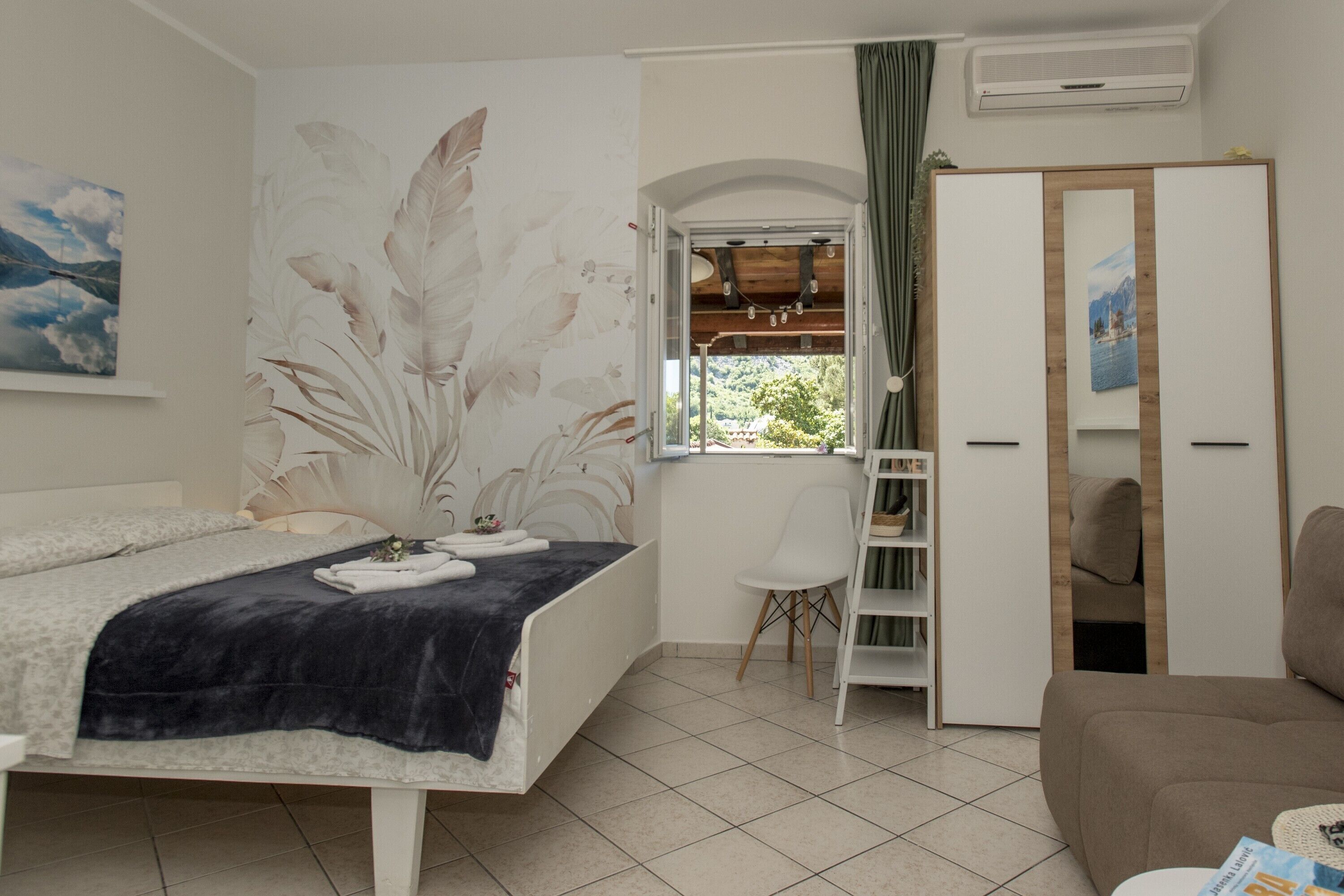 Een slaapkamer met een bed, een kast, een stoel en een raam met uitzicht op groen.