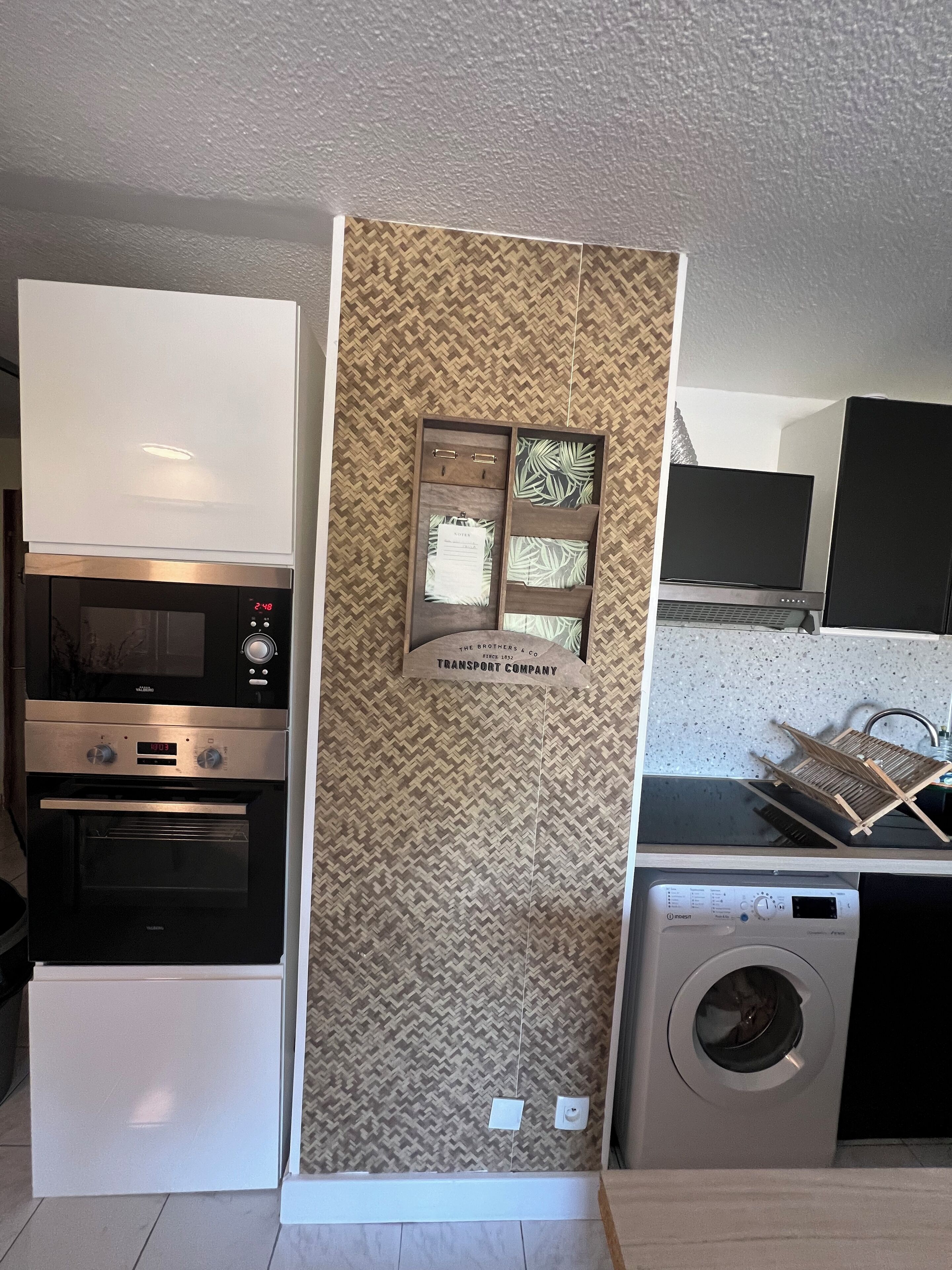 A compact kitchen with a microwave, oven, and a washing machine.