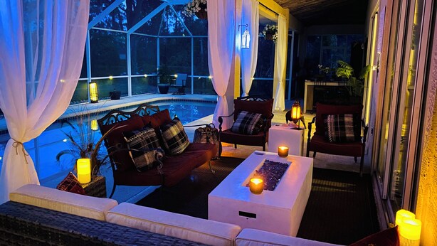 A cozy indoor seating area with a pool view, featuring a sofa, chairs, and a coffee table. - Fishing dock, pet friendly, heated pool. Every sport channel !!!  (Palm Coast)