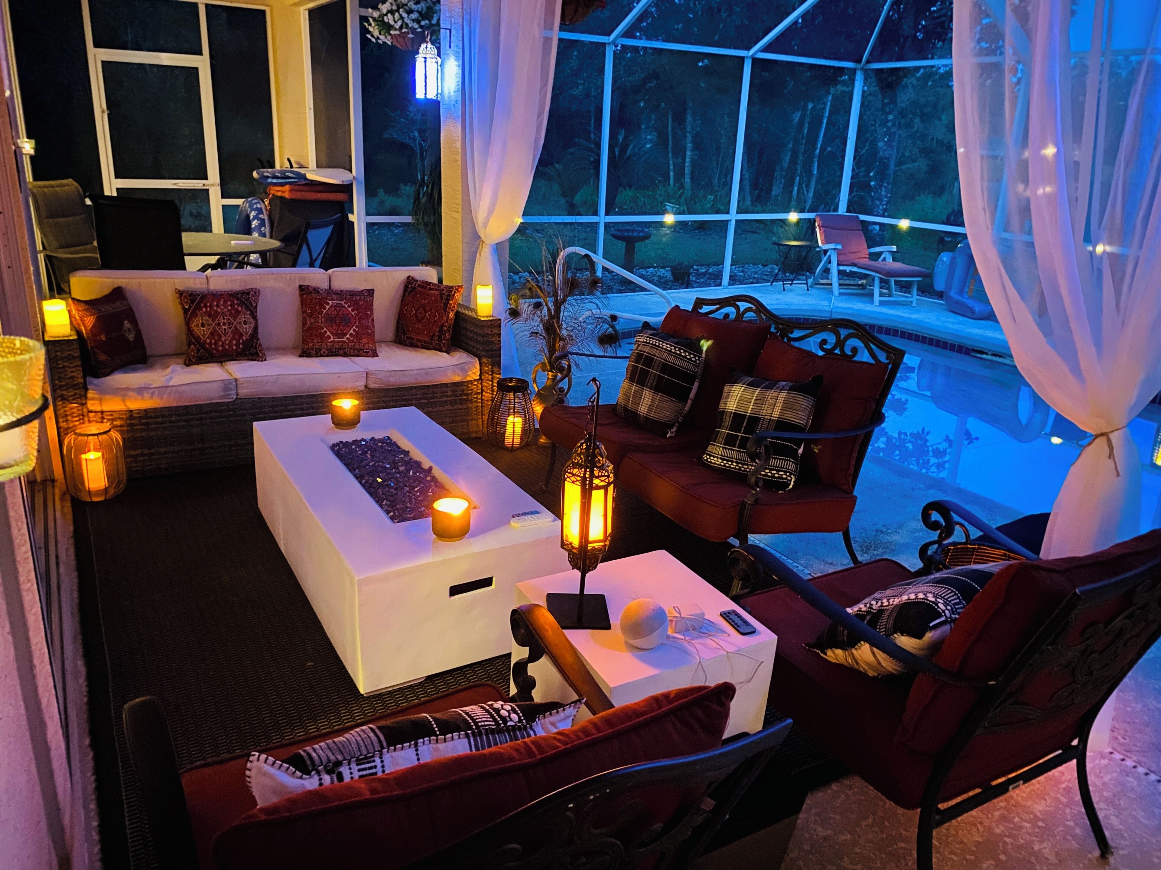 A cozy outdoor seating area with a sofa, chairs, and a coffee table, surrounded by candles and lanterns.