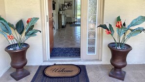 A house entrance with a number '30' on the wall, a welcome mat, and two potted plants with flowers. - Fishing dock, pet friendly, heated pool. Every sport channel !!!  (Palm Coast)