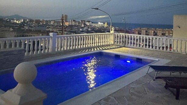 Une piscine sur le toit offrant une vue sur le paysage urbain au crépuscule.