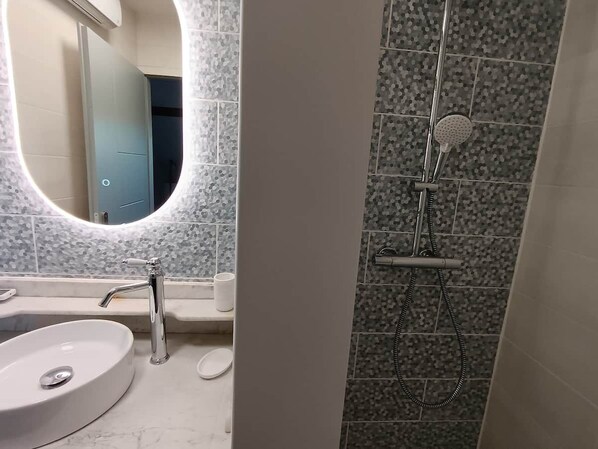 A bathroom with a white sink, a mirror, and a shower with a handheld showerhead. - Elegant house from the 1930s, 180 m² (Dernancourt)