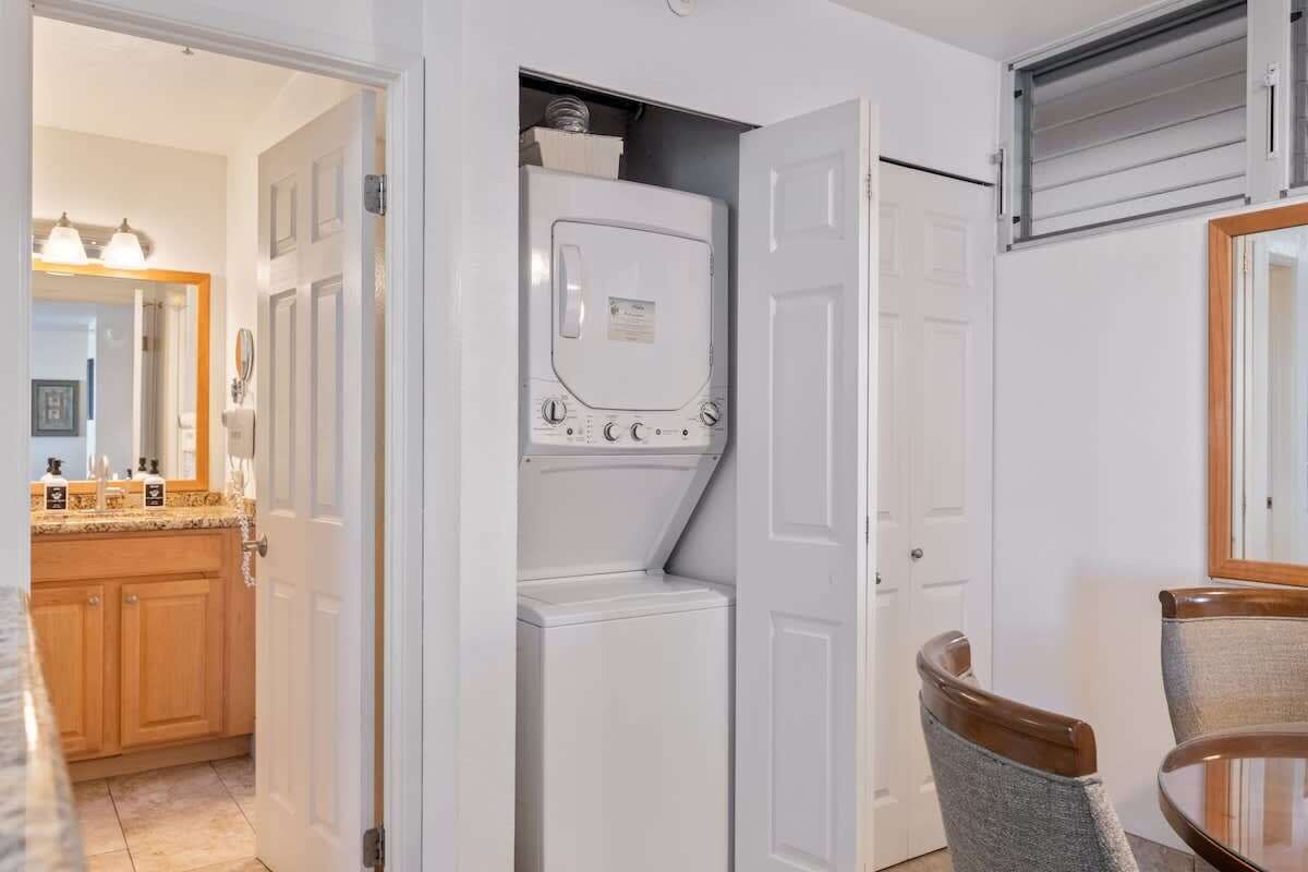 A laundry room with a washer and dryer, a wooden cabinet, and a dining area with a table and chairs.