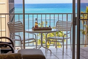 A balcony with a table set for two, overlooking a beach.