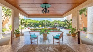 A covered outdoor seating area with a view of a parking lot and greenery.