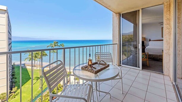 A balcony with a table, chairs, and a bottle.