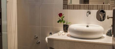 A bathroom with a white sink, a mirror, a towel rack, a toilet, and a small stool.