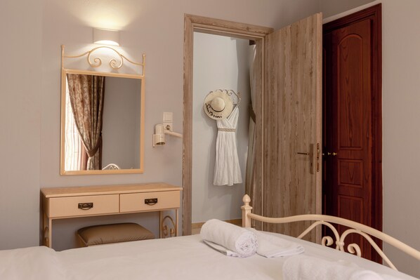 Un dormitorio con cama, mesita de noche, espejo, armario y puerta.