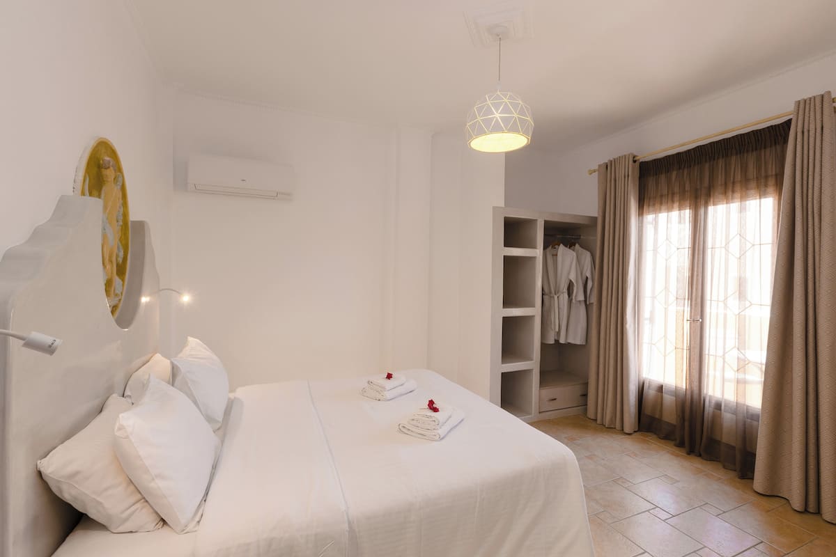A hotel room with a bed, a wardrobe, a mirror, and a window with curtains.