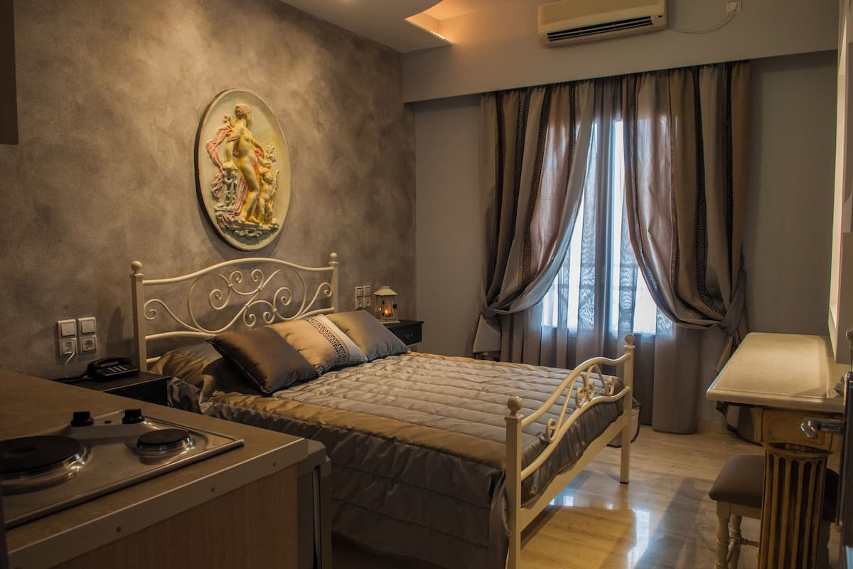 A bedroom with a bed, bedside table, lamp, and a painting on the wall.