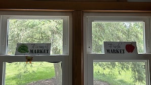 A farmhouse sign above two windows with 'Farmer's Market' signs on the sills. - Cozy and Clean Farmhouse in Mountains near Gettysburg. No extra cleaning fees! (Orrtanna)