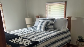 A bedroom with a bed, a bedside table, a lamp, a window with blinds, and a small round table with a plant. - Cozy and Clean Farmhouse in Mountains near Gettysburg. No extra cleaning fees! (Orrtanna)