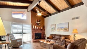 Un salón amplio con chimenea, pisos de madera y un techo alto con vigas a la vista.
