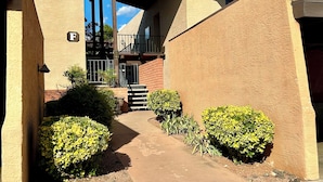Un edificio con fachada color beige, un acceso cubierto y una señal con la letra 'F' visible.