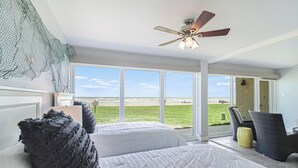 A bedroom with two beds, a ceiling fan, and a view of the beach. - Gulfstream Condos Unit 112 | Ground Floor | Gulf Front Views (Corpus Christi)