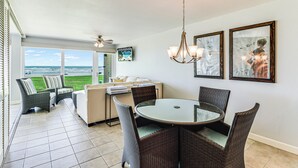 A dining area with a round table, wicker chairs, and a ceiling fan. - Gulfstream Condos Unit 112 | Ground Floor | Gulf Front Views (Corpus Christi)