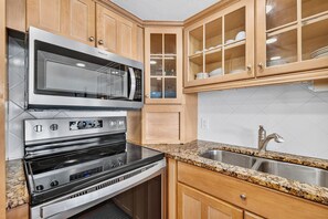 A kitchen with stainless steel appliances, wooden cabinets, and a granite countertop. - Gulfstream Condos Unit 115 | Gulf Front View | Beachfront Patio (Corpus Christi)