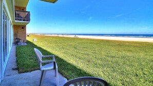 Un balcone con vista sulla spiaggia, un prato e una sedia.