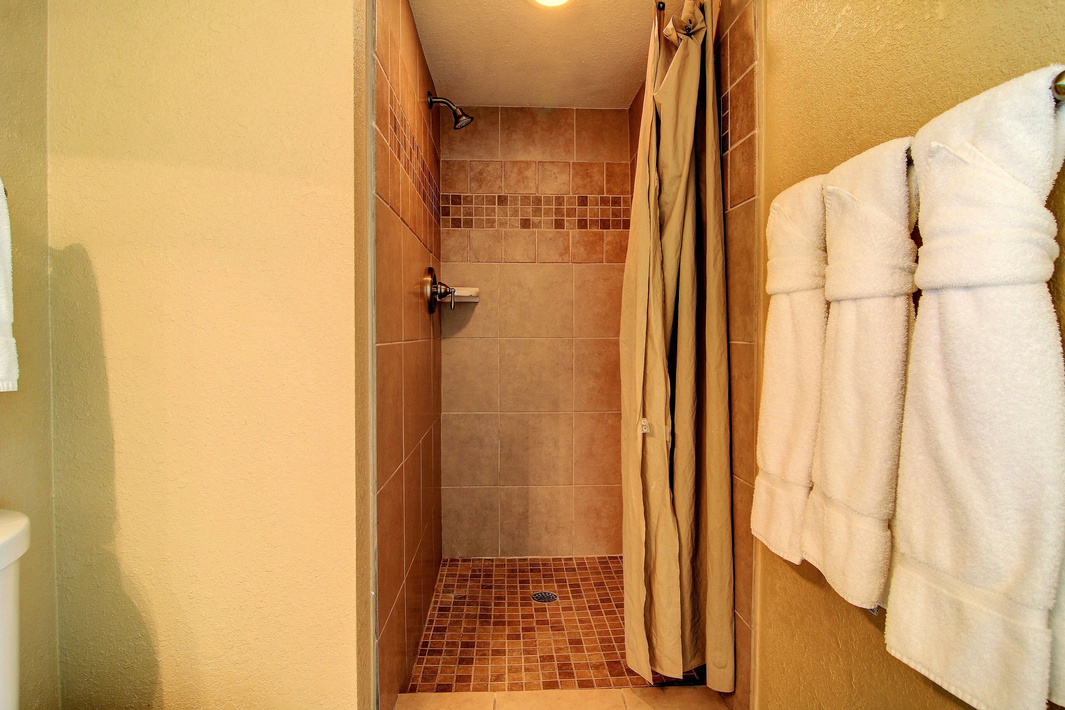 A bathroom with a shower, tiled walls, and a towel rack with towels.