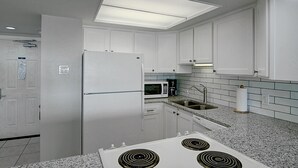 A modern kitchen with white cabinets, a built-in microwave, a stainless steel sink, and a gas stove. - Gulfstream Condos Unit 205 | Corner Unit with Beachfront Balcony (Corpus Christi)