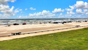 A beach with a clear sky, a sandy shore, and several umbrellas. - Gulfstream Condos Unit 205 | Corner Unit with Beachfront Balcony (Corpus Christi)