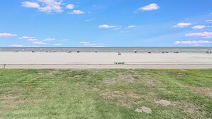 Een breed, open strand met een heldere lucht en enkele wolken.