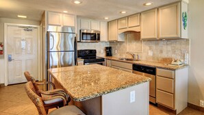 A kitchen with white cabinets, stainless steel appliances, and a granite countertop. - Gulfstream Condos Unit 217 | Gulf-Front View with Beach Balcony & Pool (Corpus Christi)